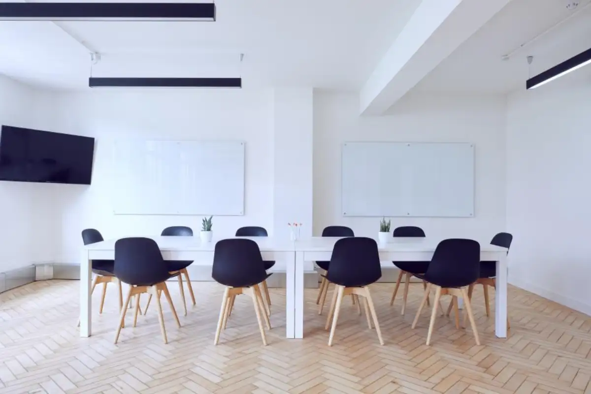 Salle de réunion claire au parquet à chevrons, table et chaises alignées