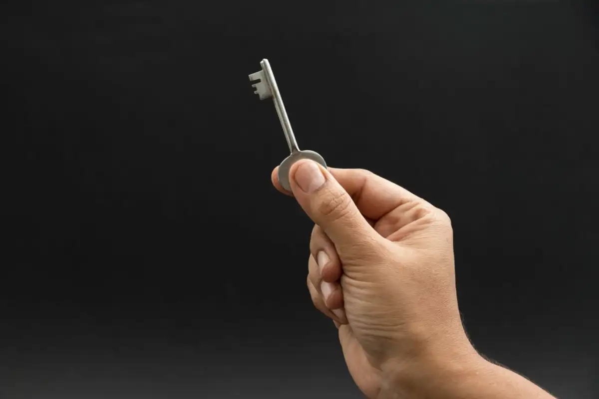 Main tendant une clé sur fond sombre
