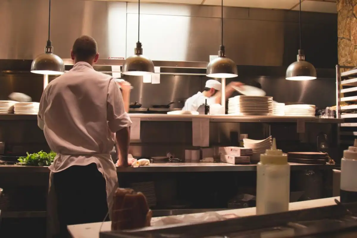 Cuisine ouverte d'un restaurant en plein service, brigade au travail sous les lampes