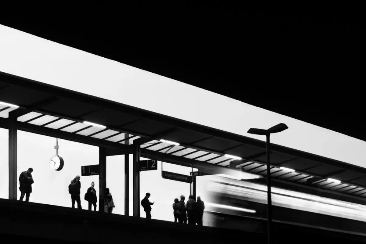 Quai de gare en contre-jour, voyageurs en attente sous la marquise