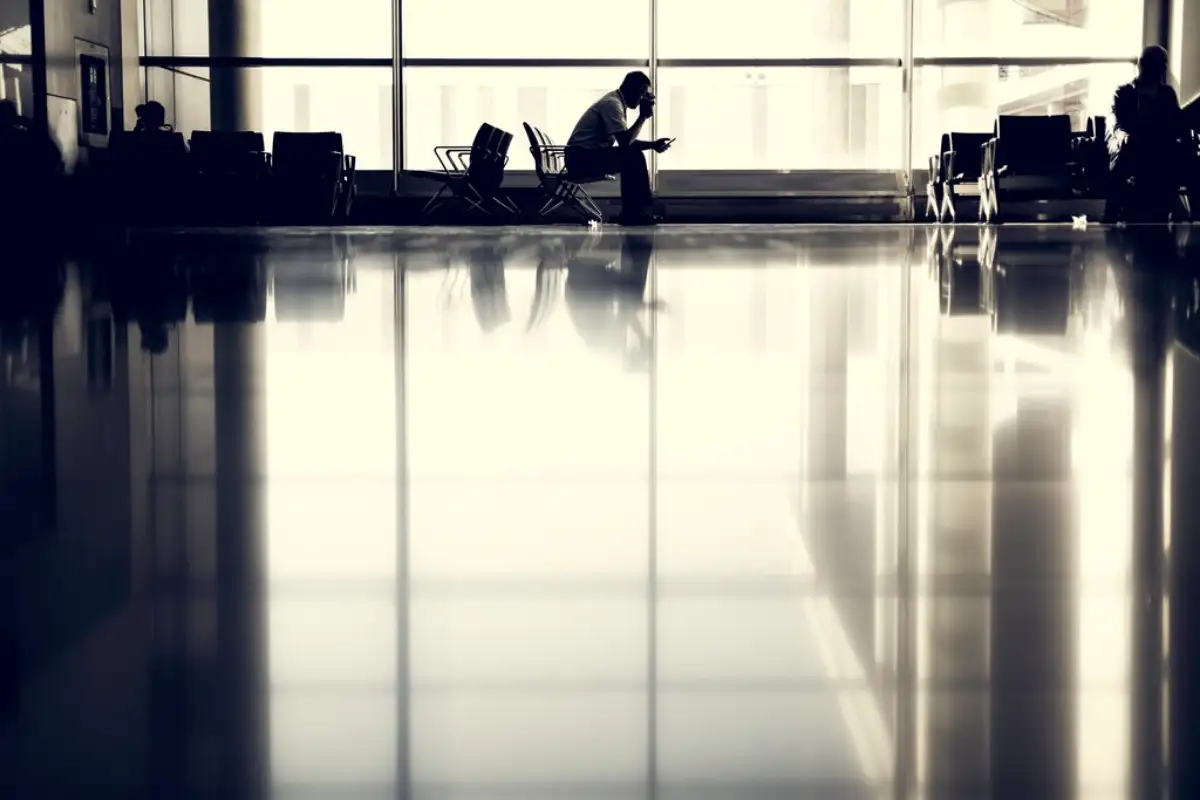 Hall d'aéroport à contre-jour, voyageurs assis en attente