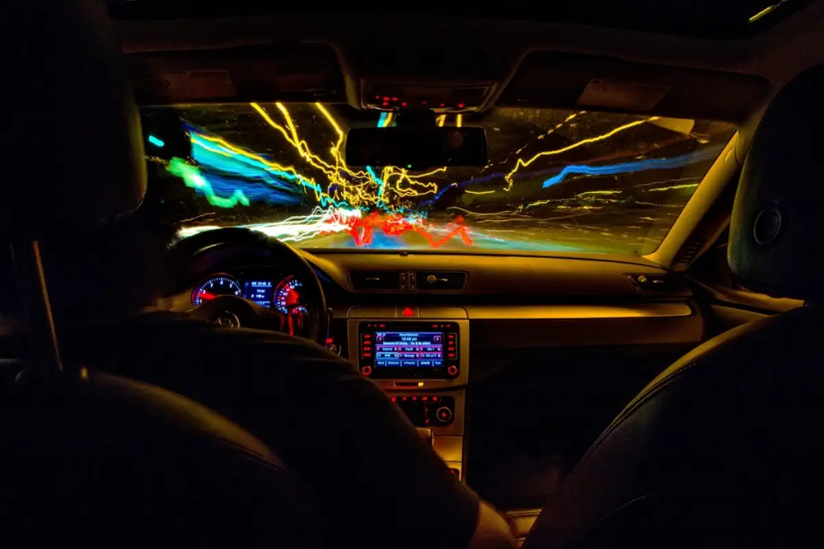 Tableau de bord éclairé d'une berline conduite de nuit en ville